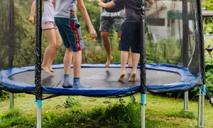 Dzieci skaczą na trampolinie, która mogłaby znaleźć się w rankingu trampolin ogrodowych. Radosna zabawa na świeżym powietrzu.