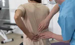 Fizjoterapeuta bada pacjentkę z bólem w odcinku lędźwiowym kręgosłupa, który mógł powstać po upadku.