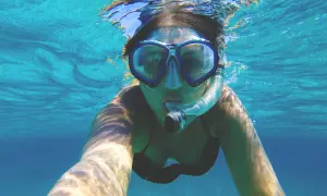 Kobieta w masce do snorkelingu, pokazująca, jak działa maska do snorkelingu, oddychając pod wodą.
