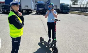 Policjantka sprawdza, czym można jeździć na kartę rowerową. Chłopiec zakłada kask na hulajnogę elektryczną.