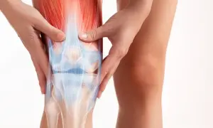 Dłonie masują bolące kolano, ukazując jego anatomię. Szukasz domowych sposobów na ból kolana?