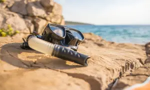 Maska i fajka do snorkelingu leżą na kamienistej plaży. To sprzęt, który pozwala odkrywać podwodny świat.