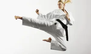Kobieta w białym karate gi wykonuje wysokie kopnięcie. Pokazuje to dynamikę i siłę różnych sztuki walki rodzaje.