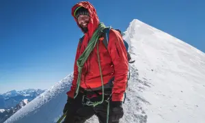 Uśmiechnięty alpinista na szczycie Mont Blanc. Zastanawiasz się, ile kosztuje wejście na Mont Blanc? To przygoda życia!