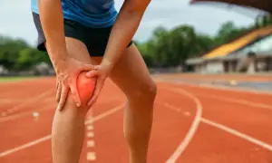 Biegaczka z bólem kolana, wskazującym na lateralizację rzepki, na bieżni stadionu.