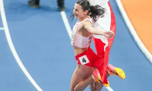 Polska biegaczka w skoku radości, z biało-czerwoną flagą. Numer 4 na spodenkach.