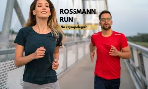 Uśmiechnięta kobieta i mężczyzna w okularach biegną po moście. Tekst "ROSSMANN RUN" sugeruje wydarzenie sportowe.