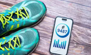 Buty sportowe i telefon z aplikacją pokazującą 9487 kroków. Czy to odpowiedź na pytanie, ile kroków dziennie powinno się robić?