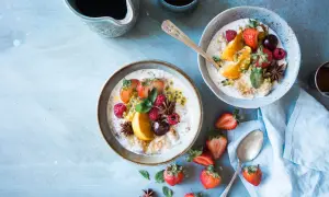 Dwa talerze owsianki z owocami (truskawki, maliny, pomarańcza, marakuja) i gwiazdkami anyżu. Idealne na śniadanie w stylu dieta wysokowęglowodanowa.
