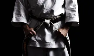 Mistrz karate w białym gi, z czarnym pasem, symbolizującym stopień mistrzowski.