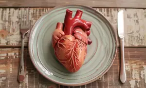 Model serca na talerzu, obok sztućców. Symbolizuje, jak ważna jest dieta na serce dla zdrowia.