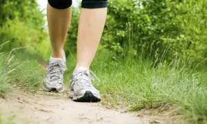 Nogi w butach sportowych na ścieżce leśnej, przygotowane do marszobiegu.