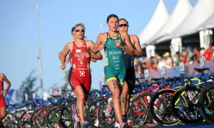 Trzy zawodniczki biegną w zawodach triathlonowych. To dyscyplina łącząca pływanie, jazdę na rowerze i bieg.