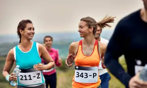 Uśmiechnięte biegaczki na jednym z półmaratonów w Polsce. W tle inni uczestnicy biegu.