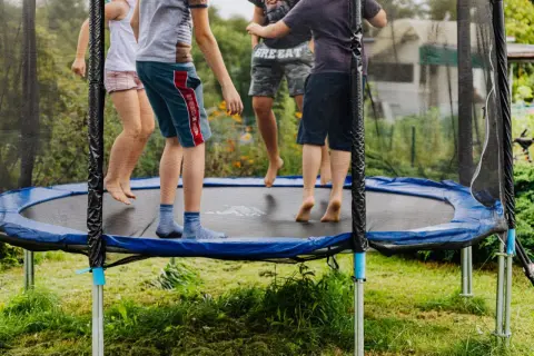 Dzieci skaczą na trampolinie, która mogłaby znaleźć się w rankingu trampolin ogrodowych. Radosna zabawa na świeżym powietrzu.