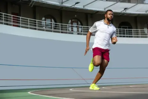Mężczyzna w sportowym stroju biegnie po bieżni. Zastanawiasz się, jak szybko biega Usain Bolt? Ten zawodnik daje z siebie wszystko!