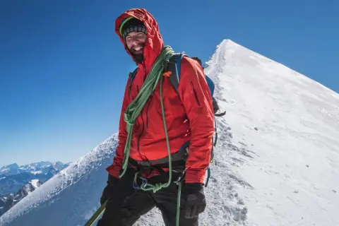 Uśmiechnięty alpinista na szczycie Mont Blanc. Zastanawiasz się, ile kosztuje wejście na Mont Blanc? To przygoda życia!