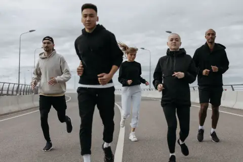 Grupa biegaczy w sportowych ubraniach, idealnych na 10 stopni. Lekkie bluzy i spodnie zapewniają komfort podczas treningu.