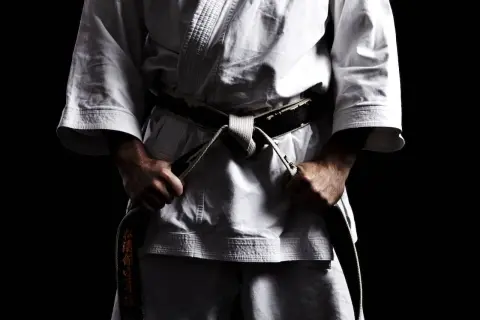Mistrz karate w białym gi, z czarnym pasem, symbolizującym stopień mistrzowski.