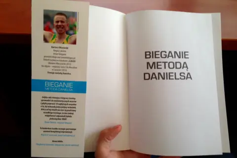 Otwarta książka z hasłem "Bieganie metodą Danielsa" na prawej stronie. Na lewej stronie zdjęcie biegacza i opis jego osiągnięć.