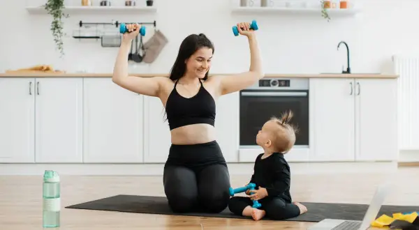 Mama i dziecko ćwiczą z hantlami w kuchni. To świetny przykład na 10 ćwiczeń z hantlami, które można wykonać w domu.