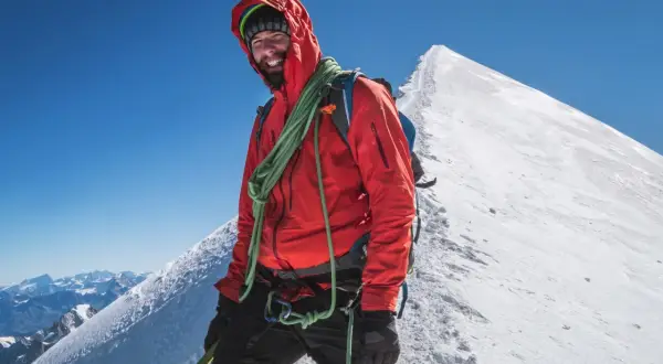 Uśmiechnięty alpinista na szczycie Mont Blanc. Zastanawiasz się, ile kosztuje wejście na Mont Blanc? To przygoda życia!