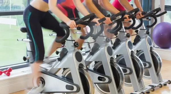 Ludzie ćwiczą na rowerach stacjonarnych. Zastanawiasz się, jaki rower stacjonarny kupić?