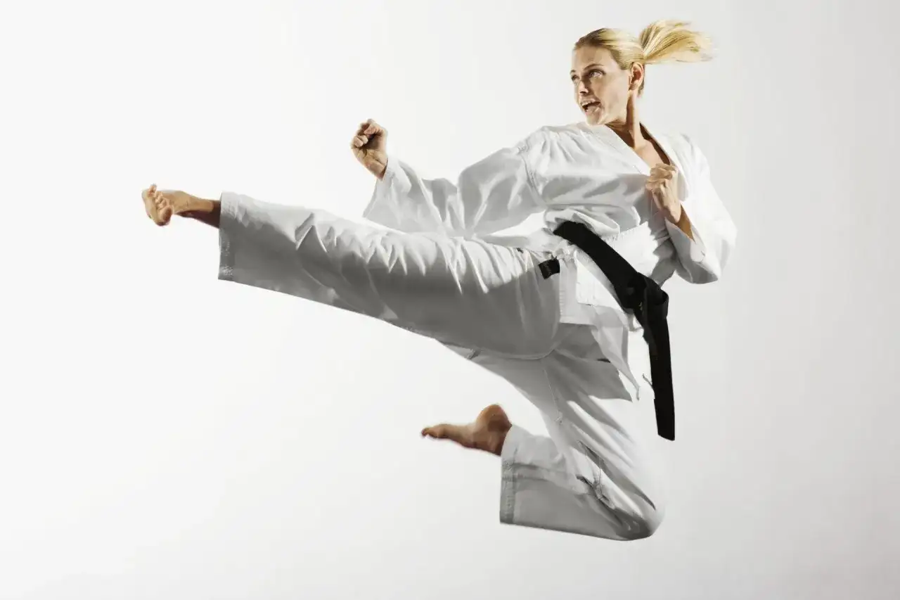 Kobieta w białym karate gi wykonuje wysokie kopnięcie. Pokazuje to dynamikę i siłę różnych sztuki walki rodzaje.