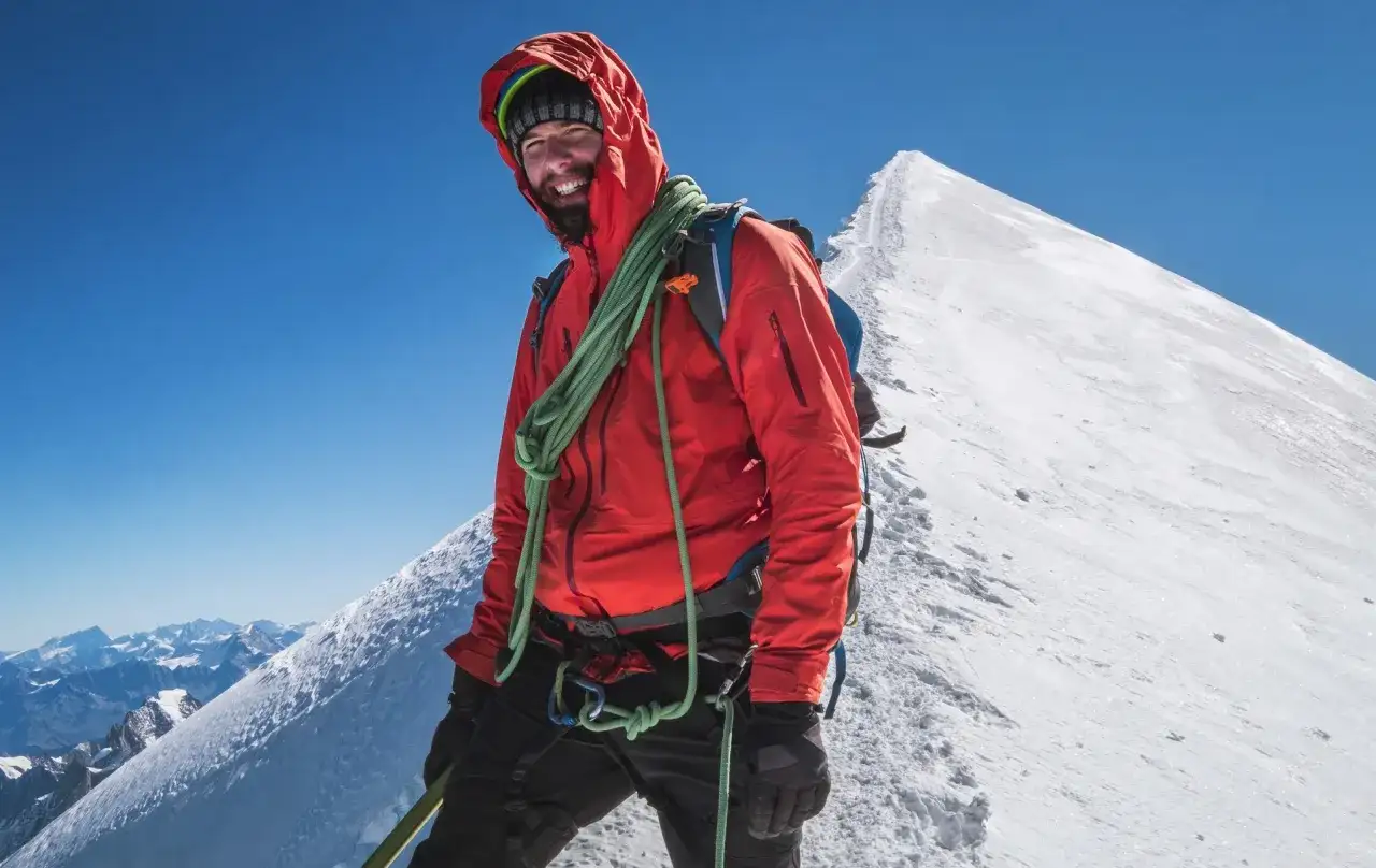 Uśmiechnięty alpinista na szczycie Mont Blanc. Zastanawiasz się, ile kosztuje wejście na Mont Blanc? To przygoda życia!