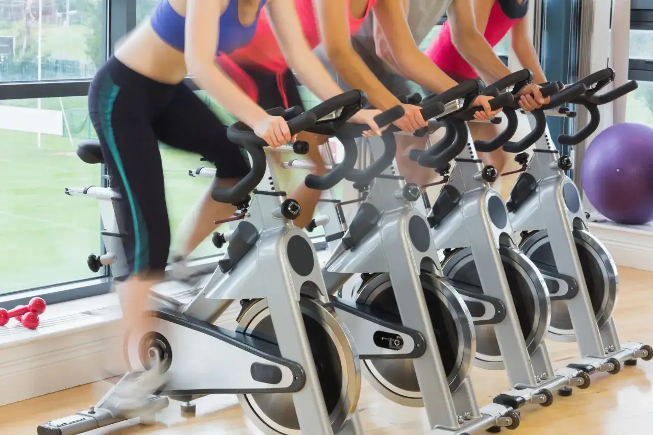 Ludzie ćwiczą na rowerach stacjonarnych. Zastanawiasz się, jaki rower stacjonarny kupić?