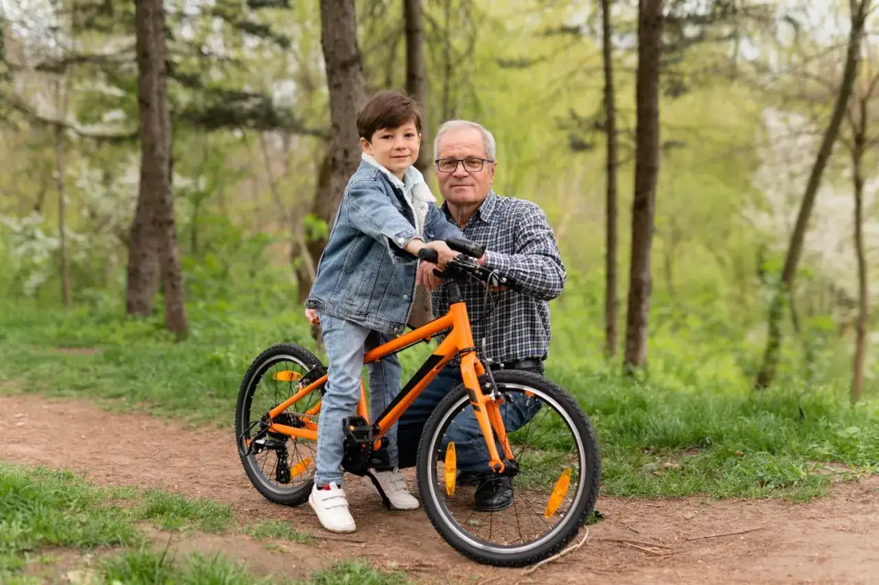 Chłopiec na rowerze z dziadkiem w lesie. Idealny rower dla 6 latka to taki, który jest lekki i łatwy w obsłudze.