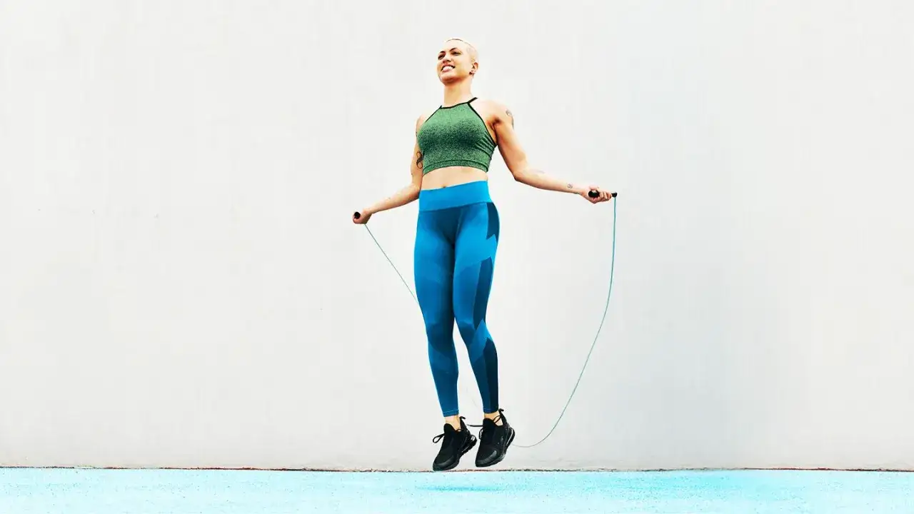 Kobieta w sportowym stroju skacze na skakance. To świetny sposób na cardio czy kardio trening.