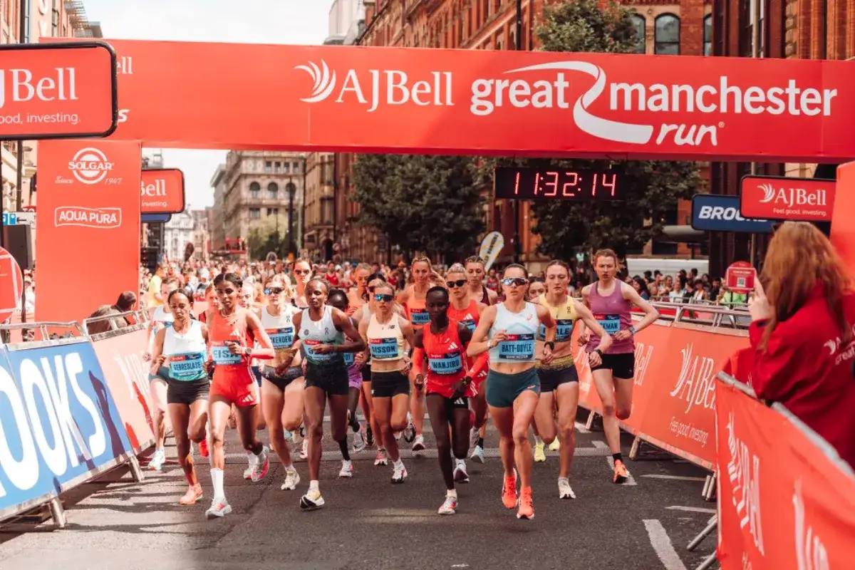 Kobiety biegną w wyścigu na 10 km, celując w rekord świata. W tle czerwony baner AJ Bell Great Manchester Run.