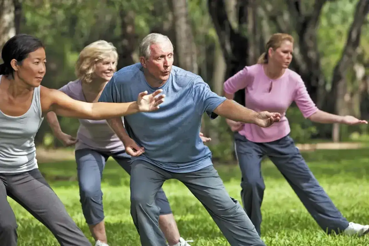 Grupa osób ćwiczy tai chi w parku. To starożytna chińska sztuka walki i forma medytacji w ruchu, która promuje zdrowie i równowagę.