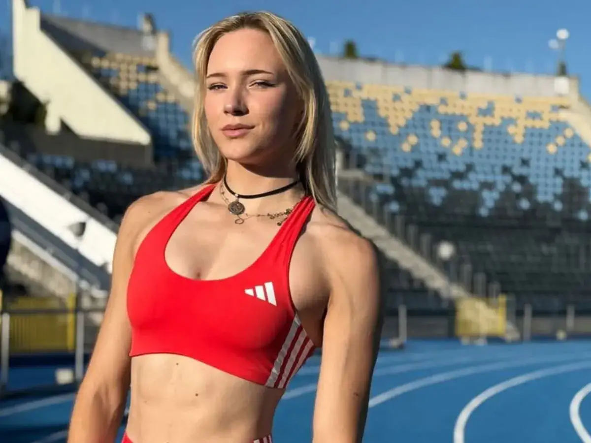 Polska biegaczka w czerwonym stroju sportowym na tle stadionu.