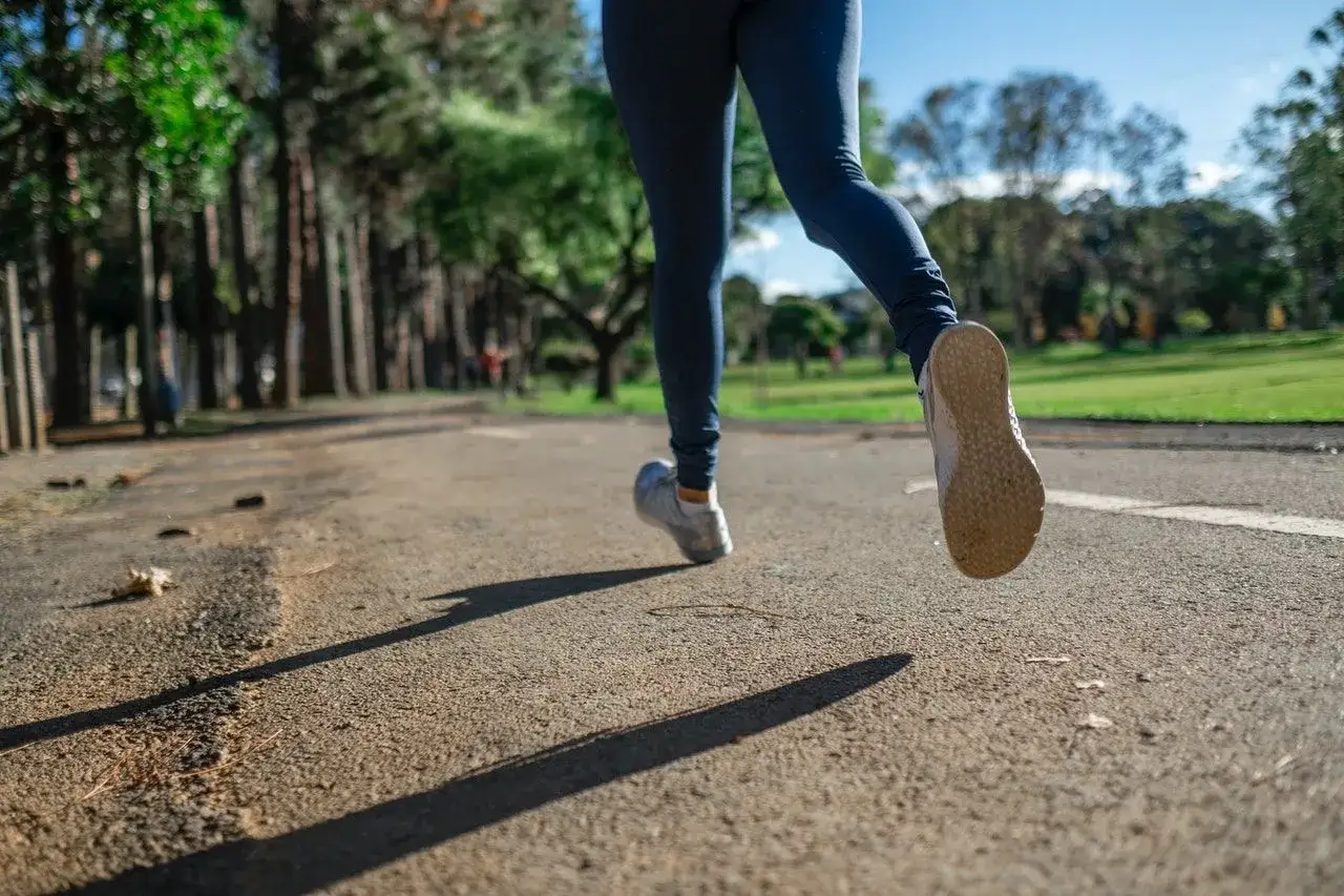 Osoba w legginsach i butach do biegania pokonuje dystans. To właśnie jest jogging – aktywność fizyczna na świeżym powietrzu.