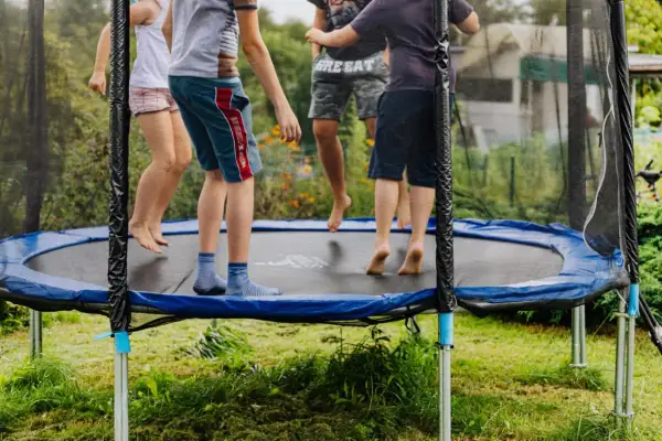 Dzieci skaczą na trampolinie, która mogłaby znaleźć się w rankingu trampolin ogrodowych. Radosna zabawa na świeżym powietrzu.