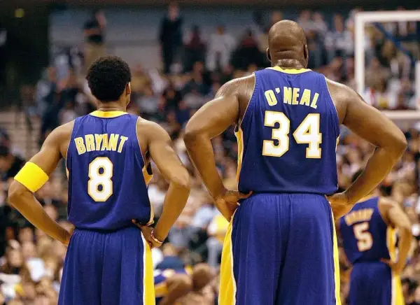 Kobe Bryant (8) i Shaquille O'Neal (34) w strojach Lakersów, czekają na rozpoczęcie meczu. Ile trwa mecz koszykówki? Zwykle 4 kwarty po 12 minut.