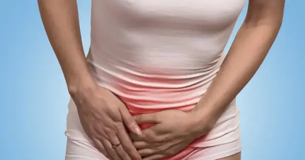 Kobieta trzyma się za brzuch, odczuwając ból w pachwinie. Czerwony obszar wskazuje na dolegliwość.