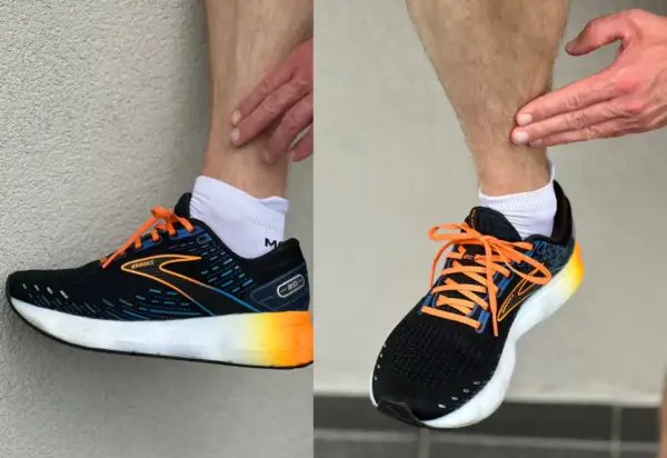 Biegacz pokazuje ból w łydce, który może być objawem shin splints. Na nogach ma czarne buty sportowe Brooks z pomarańczowymi sznurówkami.