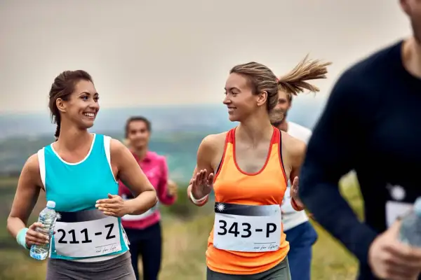 Uśmiechnięte biegaczki na jednym z półmaratonów w Polsce. W tle inni uczestnicy biegu.